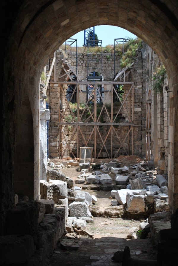 Old stone archway framing a historic structure held up by scaffolding and new shoring.